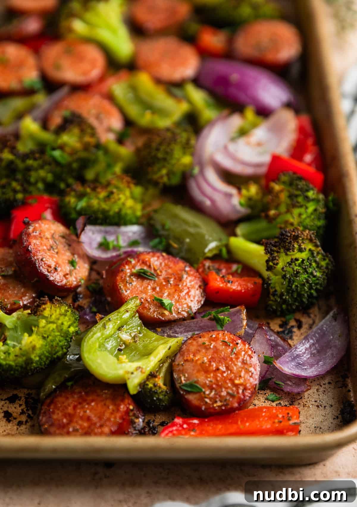 One-Pan Sausage and Veggie Sheet Pan Dinner 7 Sausages and vegetables cooked on sheet pan topped with fresh thyme and chopped parsley.