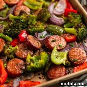 One-Pan Sausage and Veggie Sheet Pan Dinner 8 Sausages and peppers with broccoli on sheet pan after being cooked.