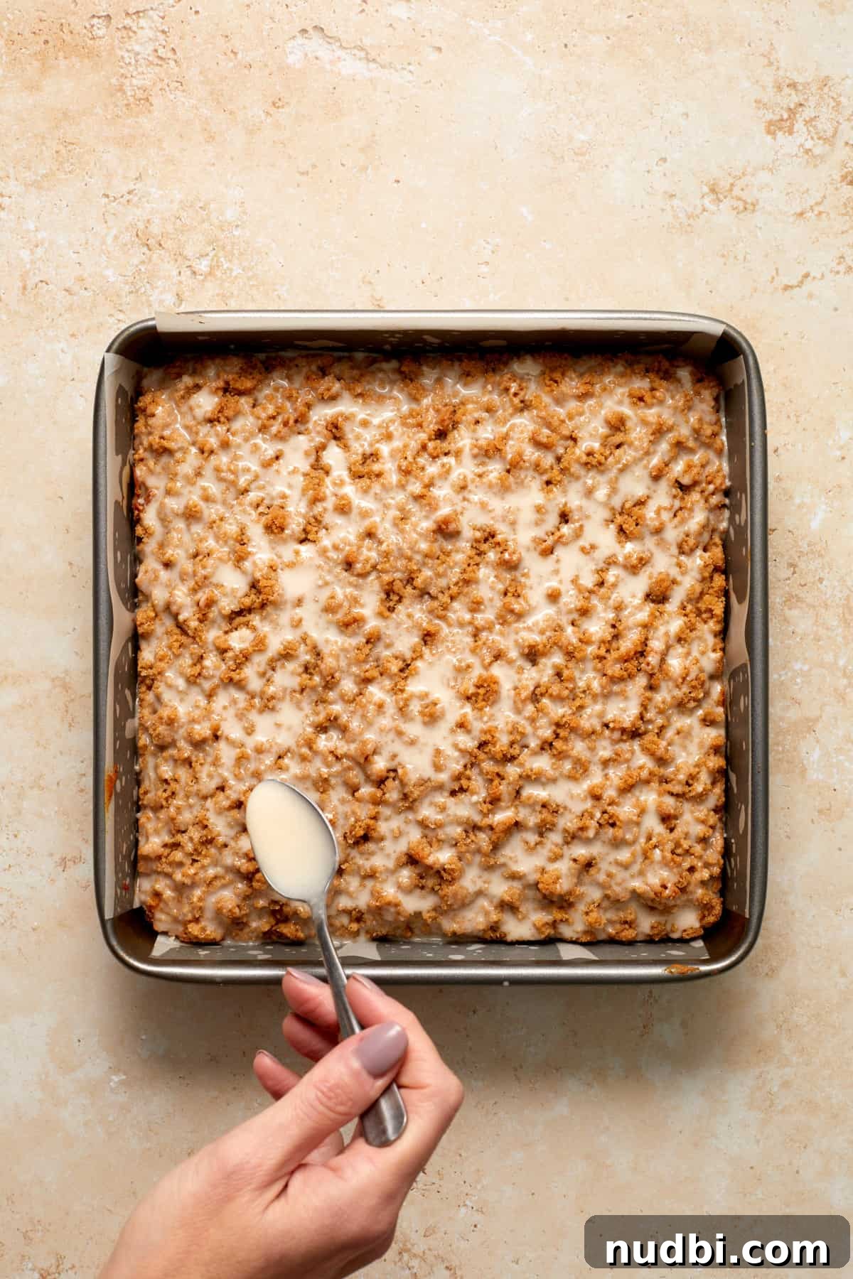 Cinnamon Streusel Pumpkin Coffee Cake Recipe for Fall Baking 15 Glaze on spoon being poured over pumpkin coffee cake.