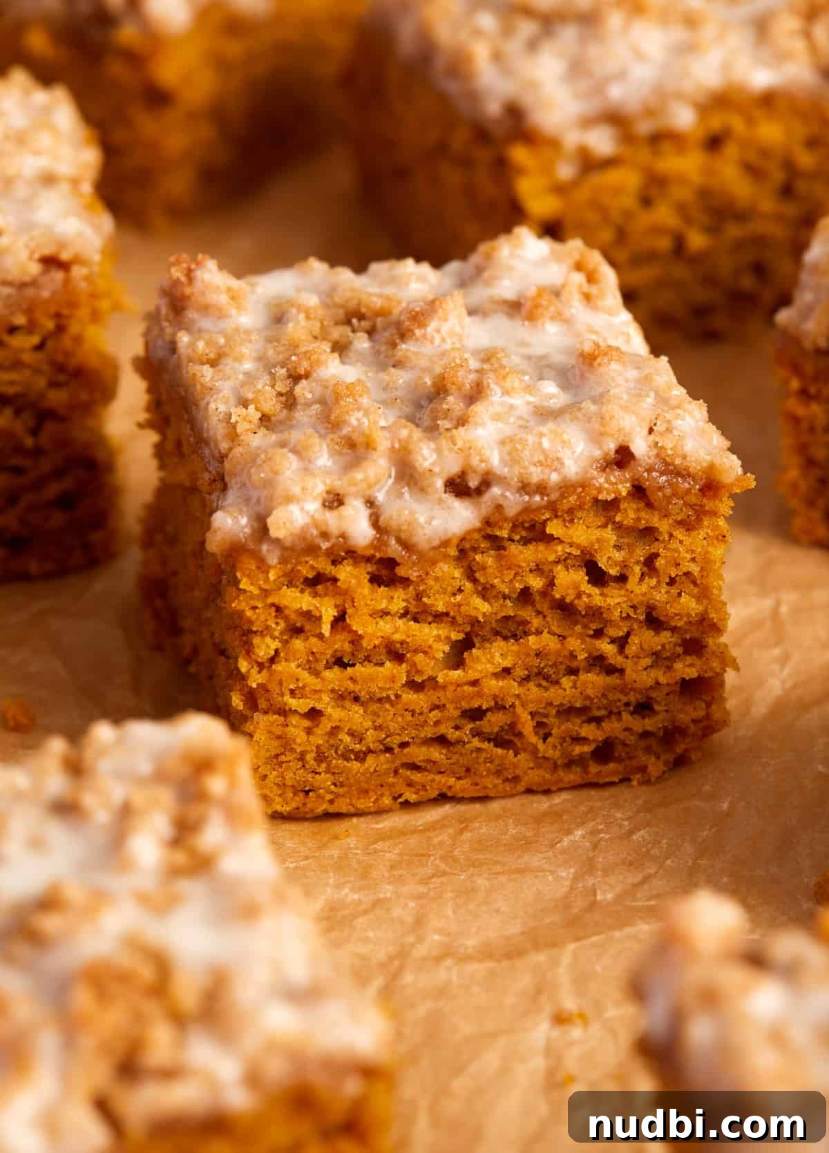 Cinnamon Streusel Pumpkin Coffee Cake Recipe for Fall Baking 3 Slice of coffee cake topped with icing and streusel on parchment paper.