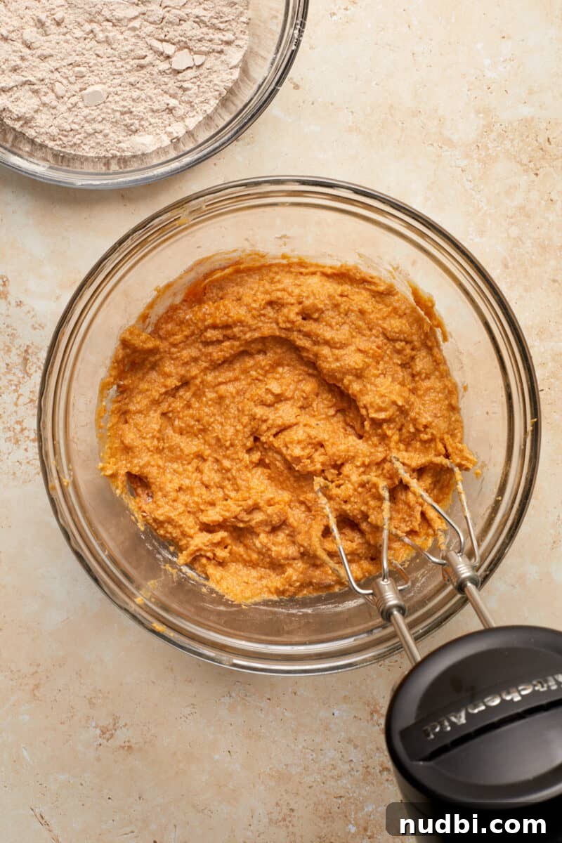Cinnamon Streusel Pumpkin Coffee Cake Recipe for Fall Baking 9 Pumpkin and part of flour mixture mixed into pumpkin coffee cake batter in glass bowl.