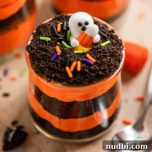 Halloween Oreo Dirt Cake Recipe for Spooky No-Bake Dessert 10 Oreo Halloween dirt cake layered in glass cup with ghost candy on top.