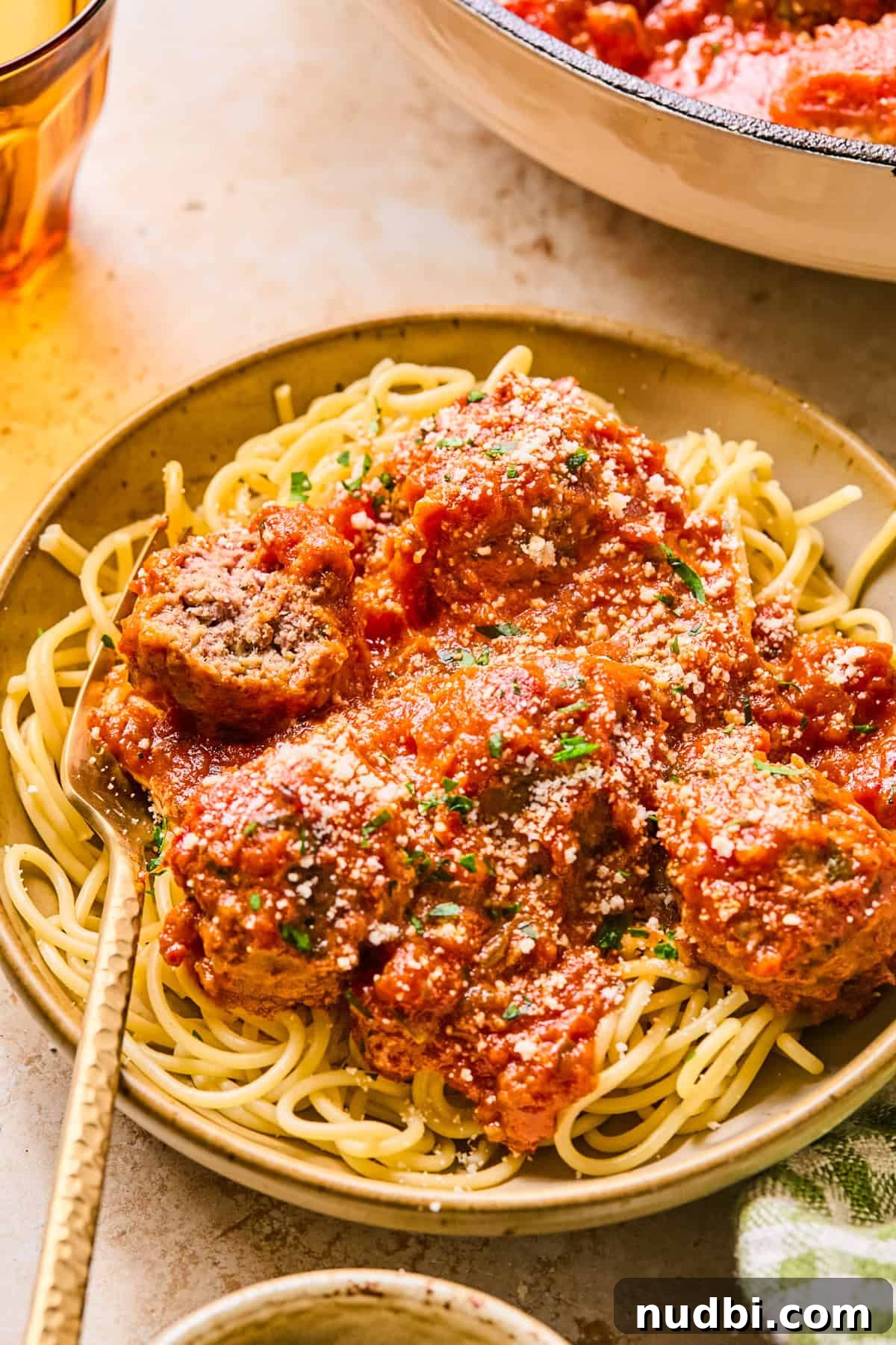 Zucchini and Beef Meatballs with Herb Sauce 2 Spaghetti and meatballs in dish with fork.
