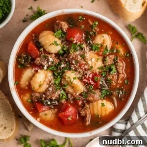 Creamy Italian Sausage Gnocchi Soup Recipe 12 Italian sausage and gnocchi soup in bowl topped with herbs and parmesan.