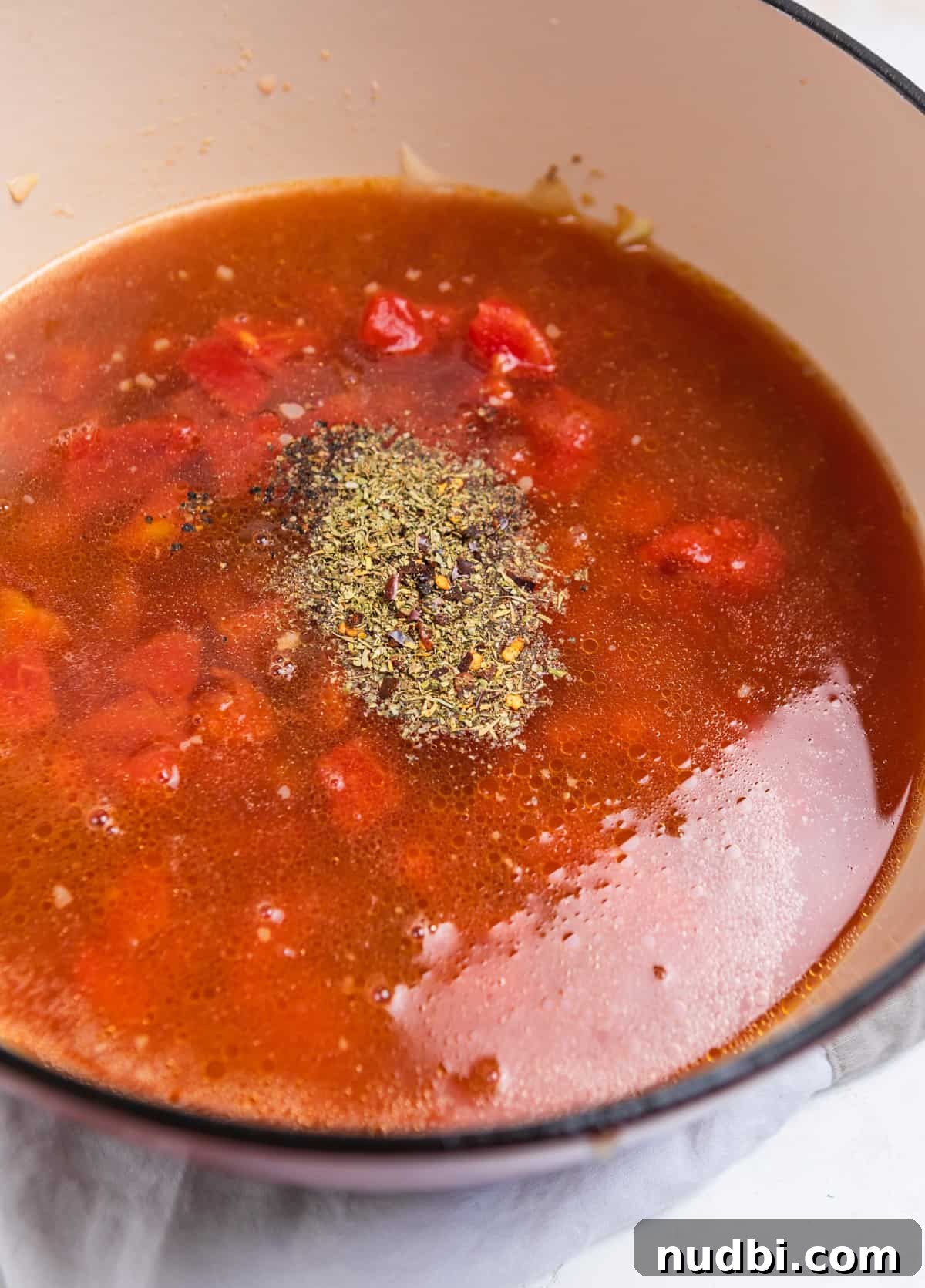 Creamy Italian Sausage Gnocchi Soup Recipe 5 Pot with broth, tomatoes and seasonings added over top.