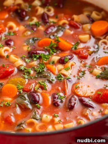 Dutch oven with vegetable soup topped with chopped parsley.