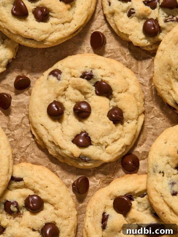 Chocolate chip cookies arranged on brown parchment paper with chocolate chips.