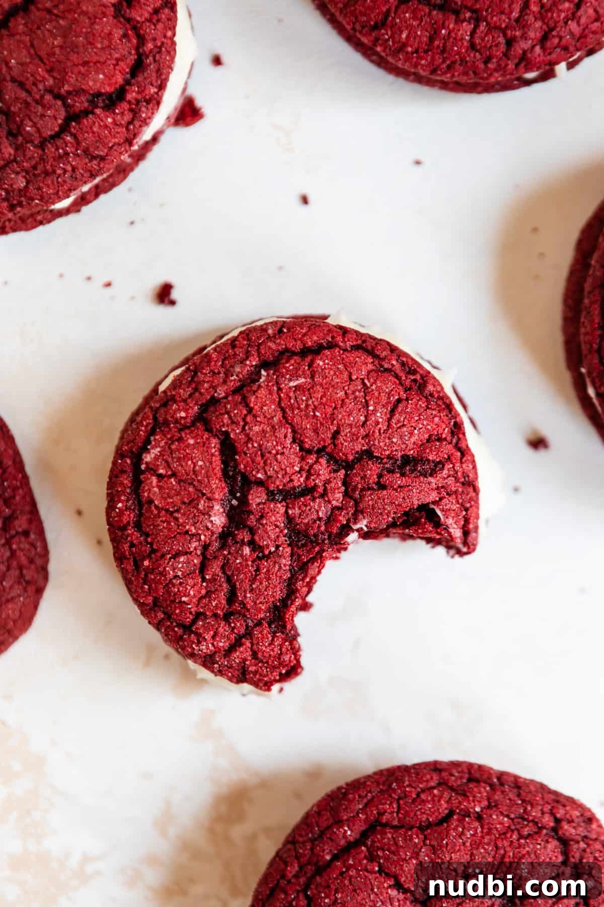Red Velvet Cake Mix Cookies with Cream Cheese Frosting 7 Overhead view of red velvet sandwich cookies with bite taken out.
