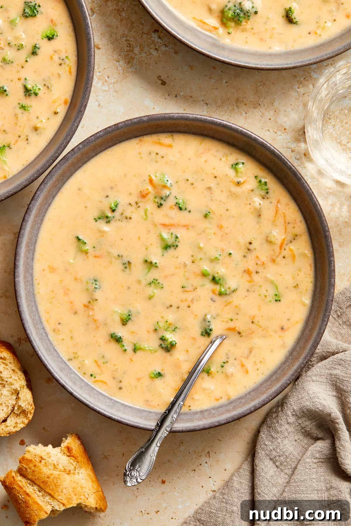 Creamy Broccoli Cheddar Soup Made in the Instant Pot 2 Gray bowl with broccoli cheddar soup with spoon along with a chunk of bread beside it.