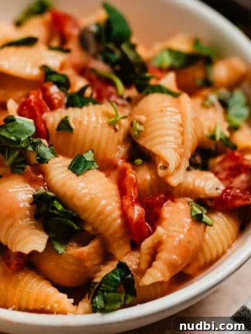 Creamy pasta with tomatoes and spinach topped with chopped fresh basil.