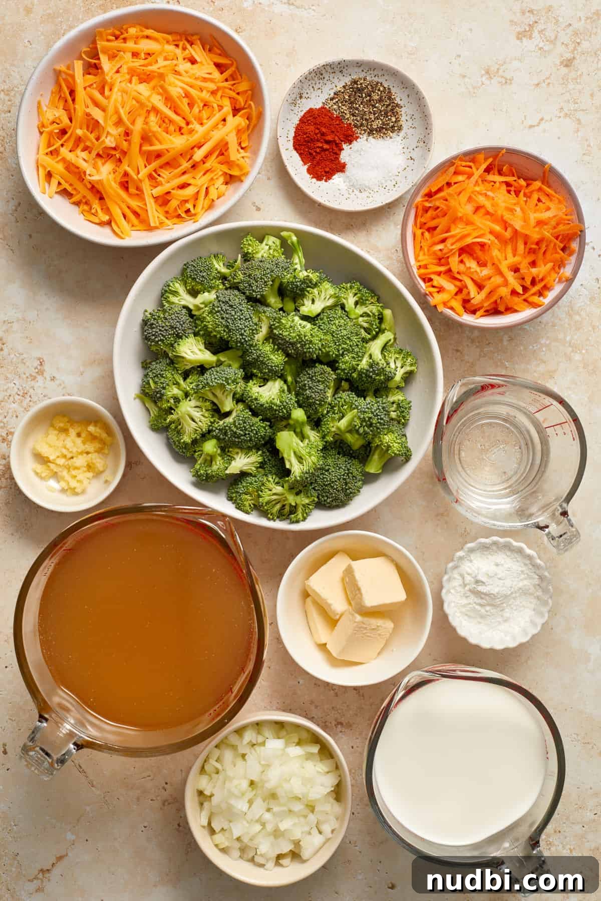 Creamy Broccoli Cheddar Soup Made in the Instant Pot 3 Carrots, cheese, butter, broth, broccoli and other soup ingredients arranged on surface to be used in recipe.