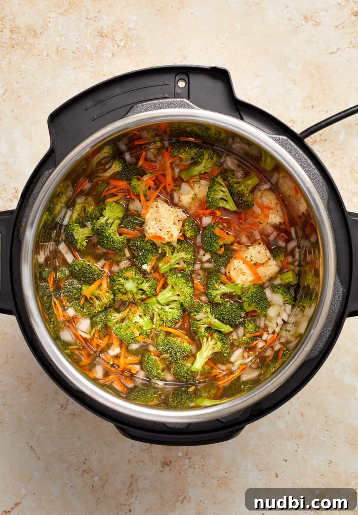 Creamy Broccoli Cheddar Soup Made in the Instant Pot 5 Broccoli, carrots, onion, broth and other soup ingredients in Instant Pot before cooking.