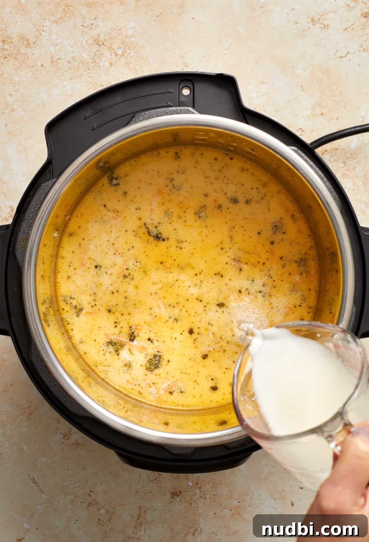 Creamy Broccoli Cheddar Soup Made in the Instant Pot 8 Corn starch slurry being poured into soup pot with broccoli cheddar soup.