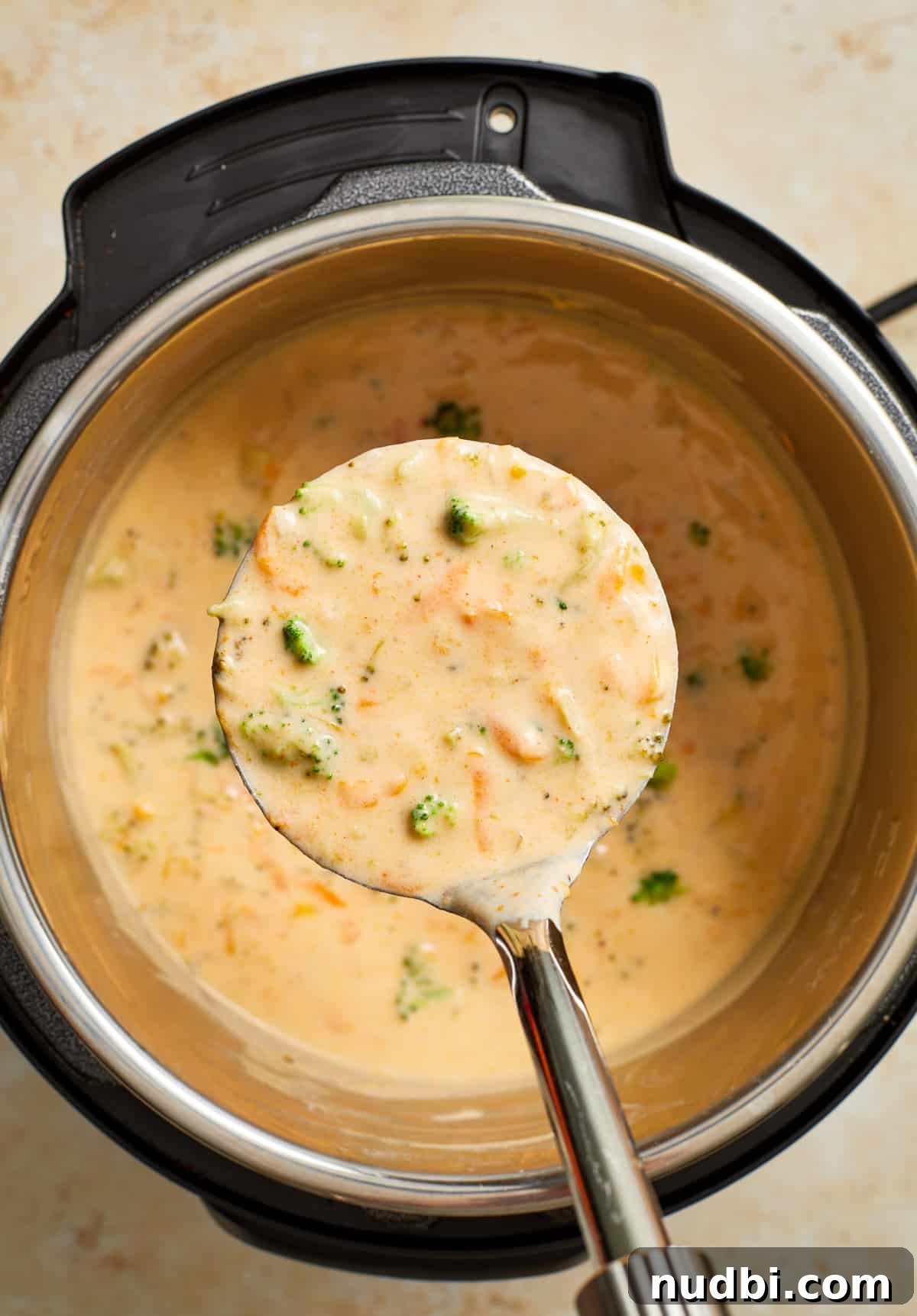 Creamy Broccoli Cheddar Soup Made in the Instant Pot 10 Ladle full of broccoli cheddar soup held over top of Instant Pot with remaining soup.