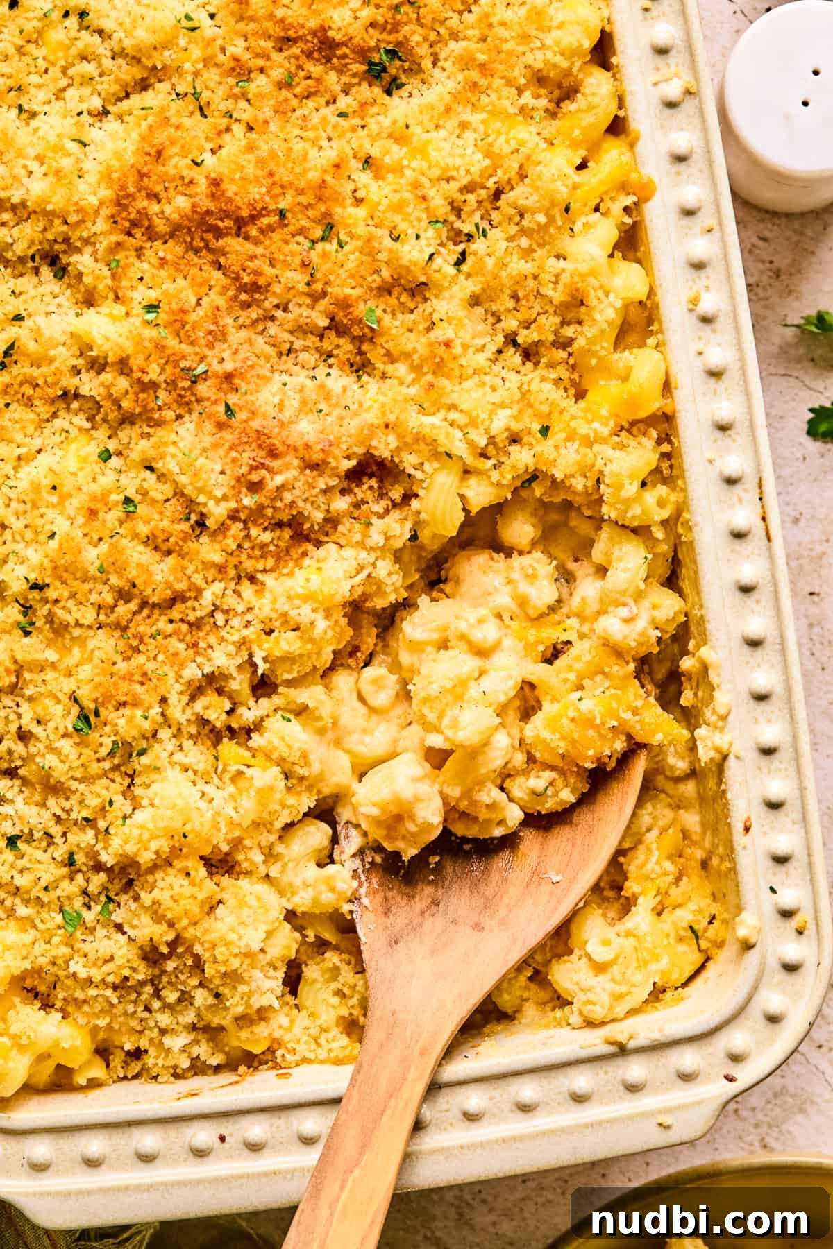 Creamy Cheddar and Gruyère Macaroni Bake 2 Cheddar gruyere macaroni and cheese in baking pan with spoon scooping into it.