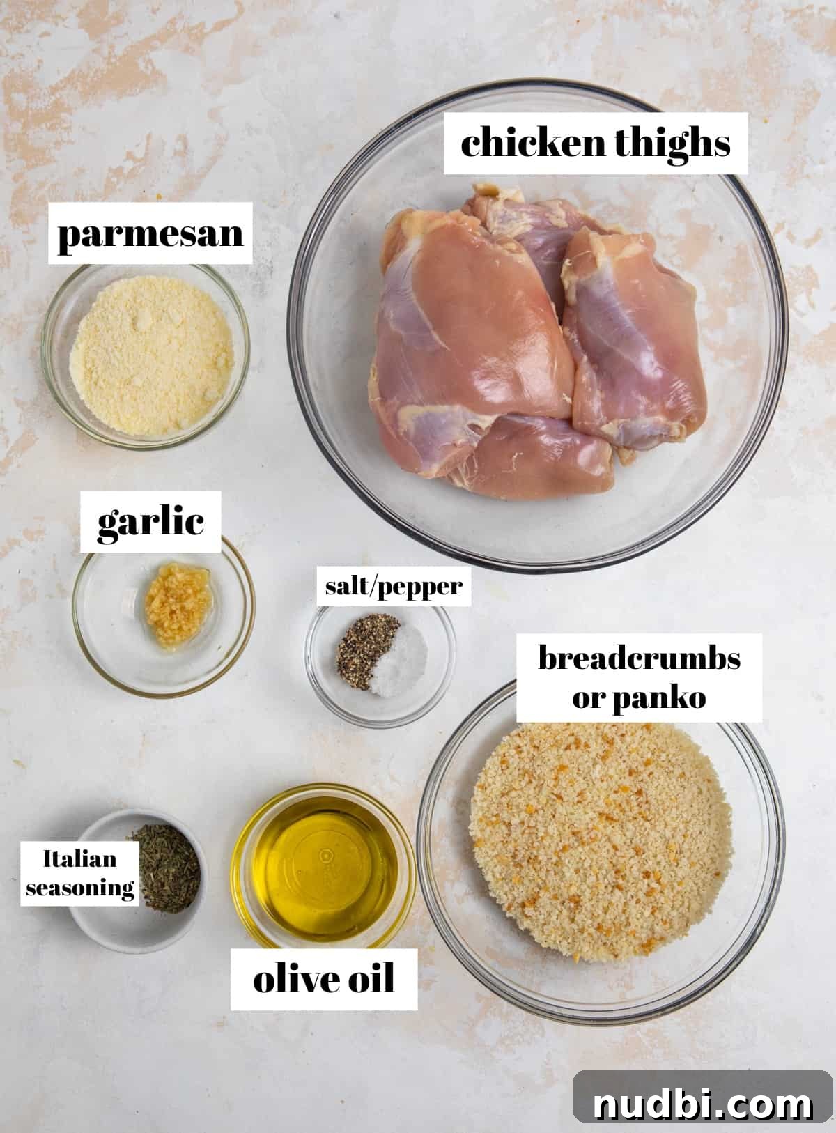 Crispy Parmesan-Crusted Air Fryer Chicken Thighs 3 Parmesan, olive oil, breadcrumbs and other ingredients labeled to make air fryer chicken thighs.