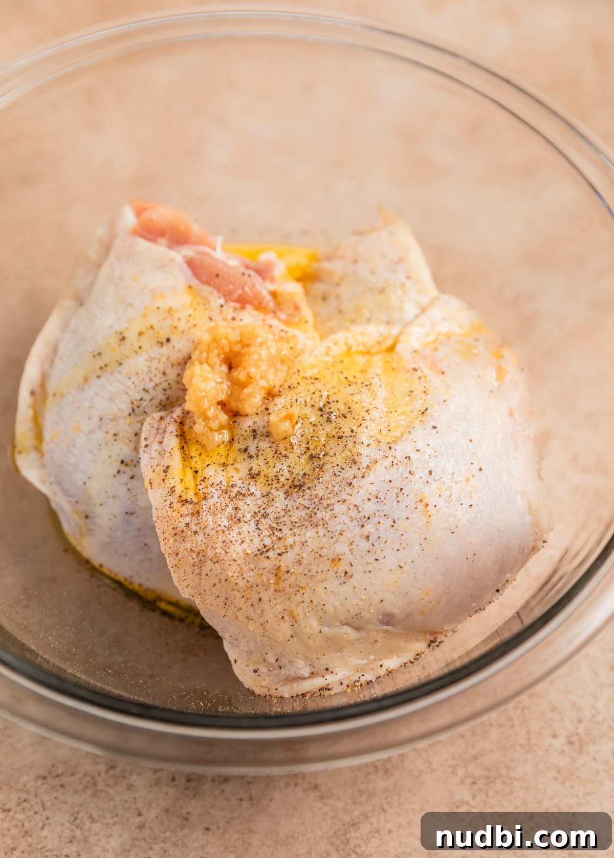 Crispy Parmesan-Crusted Air Fryer Chicken Thighs 4 Chicken thighs in glass bowl with olive oil, garlic, salt and pepper.