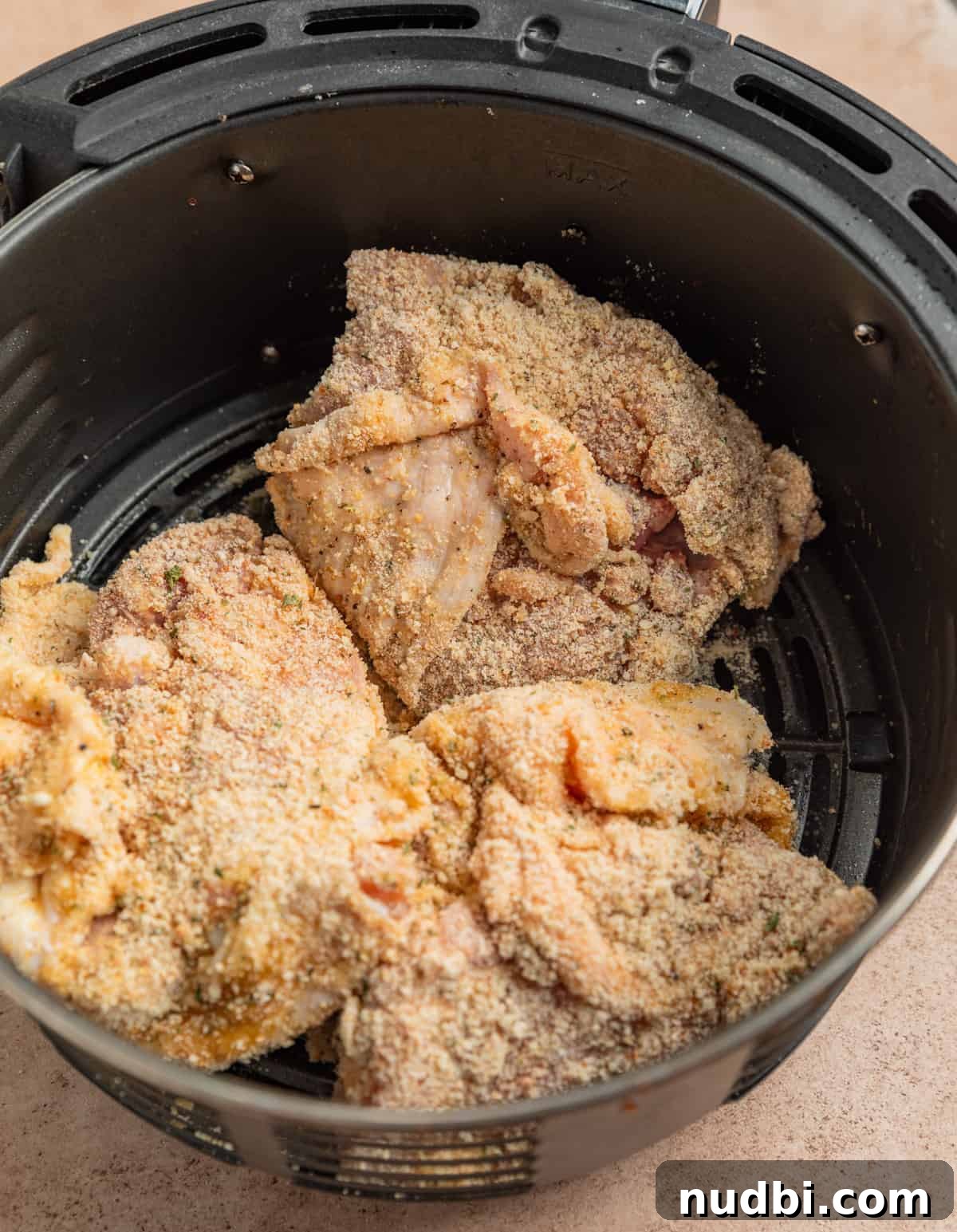 Crispy Parmesan-Crusted Air Fryer Chicken Thighs 6 Air fryer basket with breaded chicken thighs.