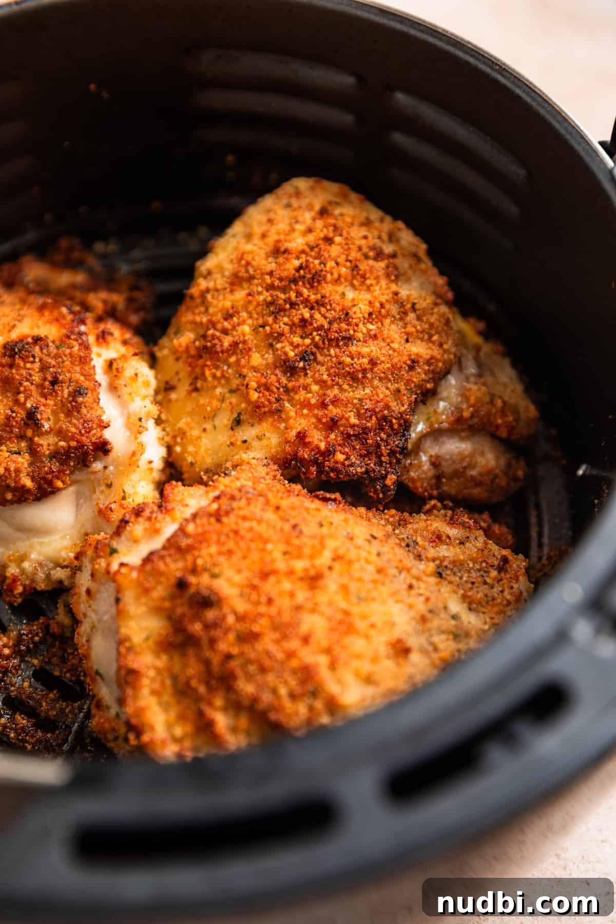 Crispy Parmesan-Crusted Air Fryer Chicken Thighs 7 Air fryer basket with crispy breaded parmesan chicken thighs.