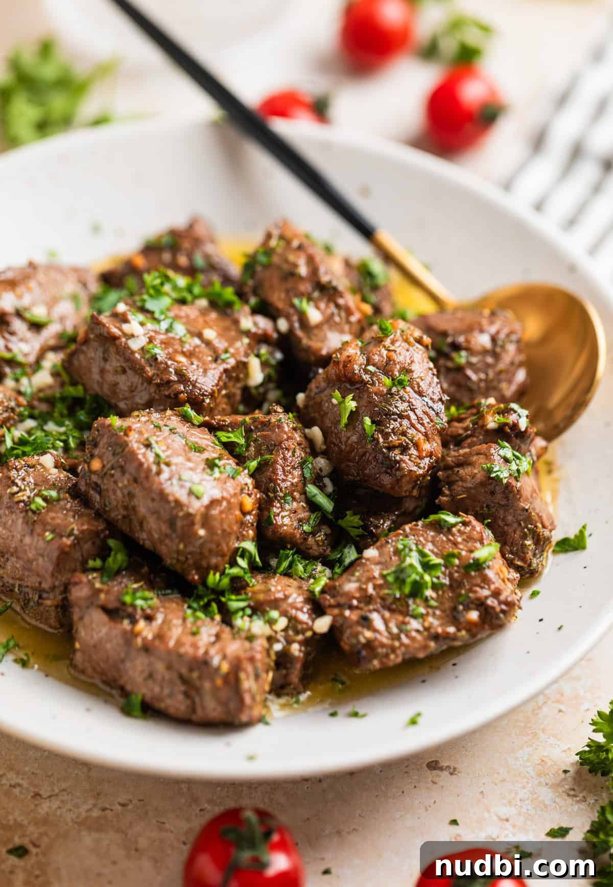 Crispy Air Fryer Steak Bites with Garlic Butter Dip 2 White serving dish with air fryer steak bites in lemon garlic butter sauce topped with chopped parsley.