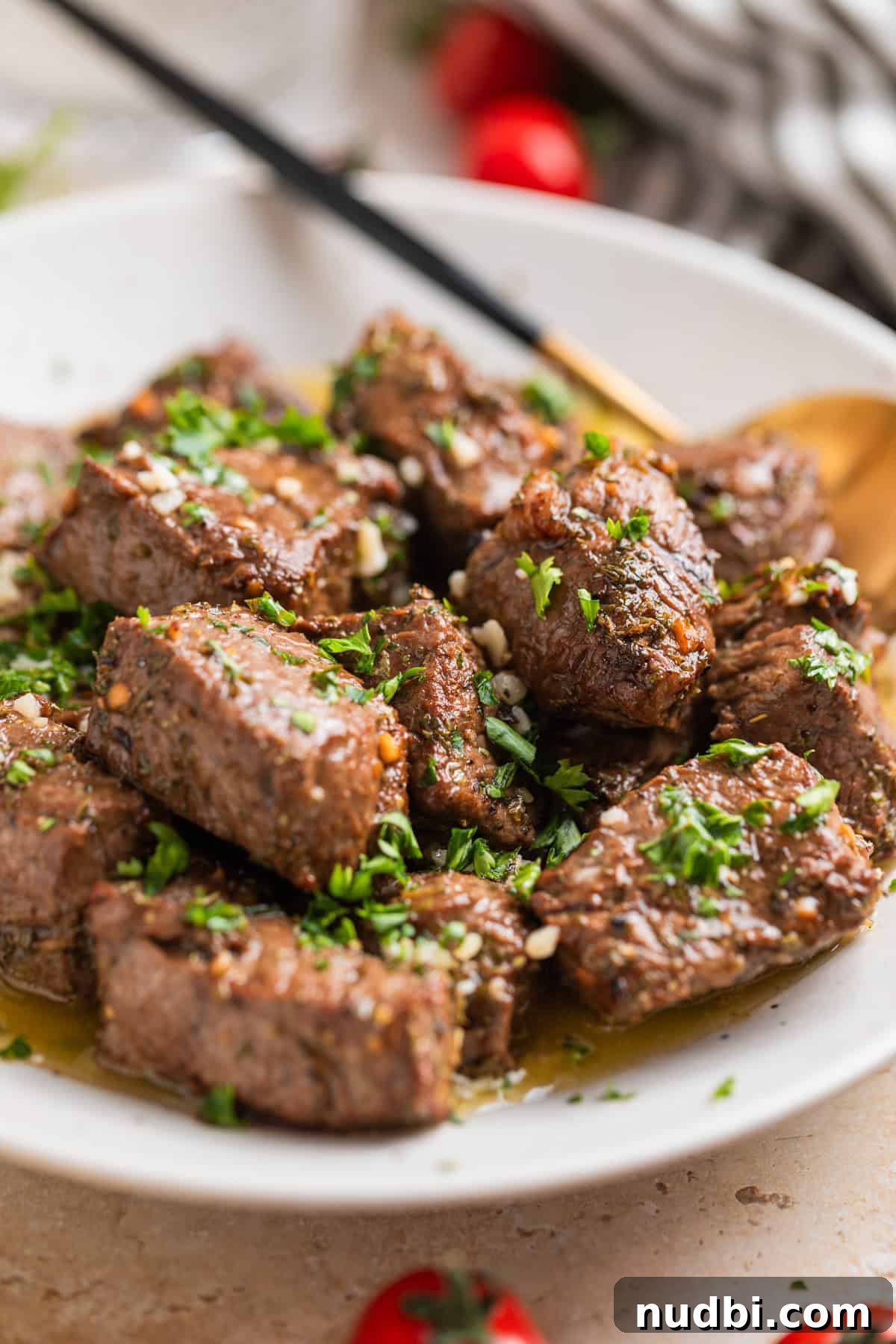 Crispy Air Fryer Steak Bites with Garlic Butter Dip 11 White ceramic plate with air fryer steak bites tossed with lemon garlic butter sauce.