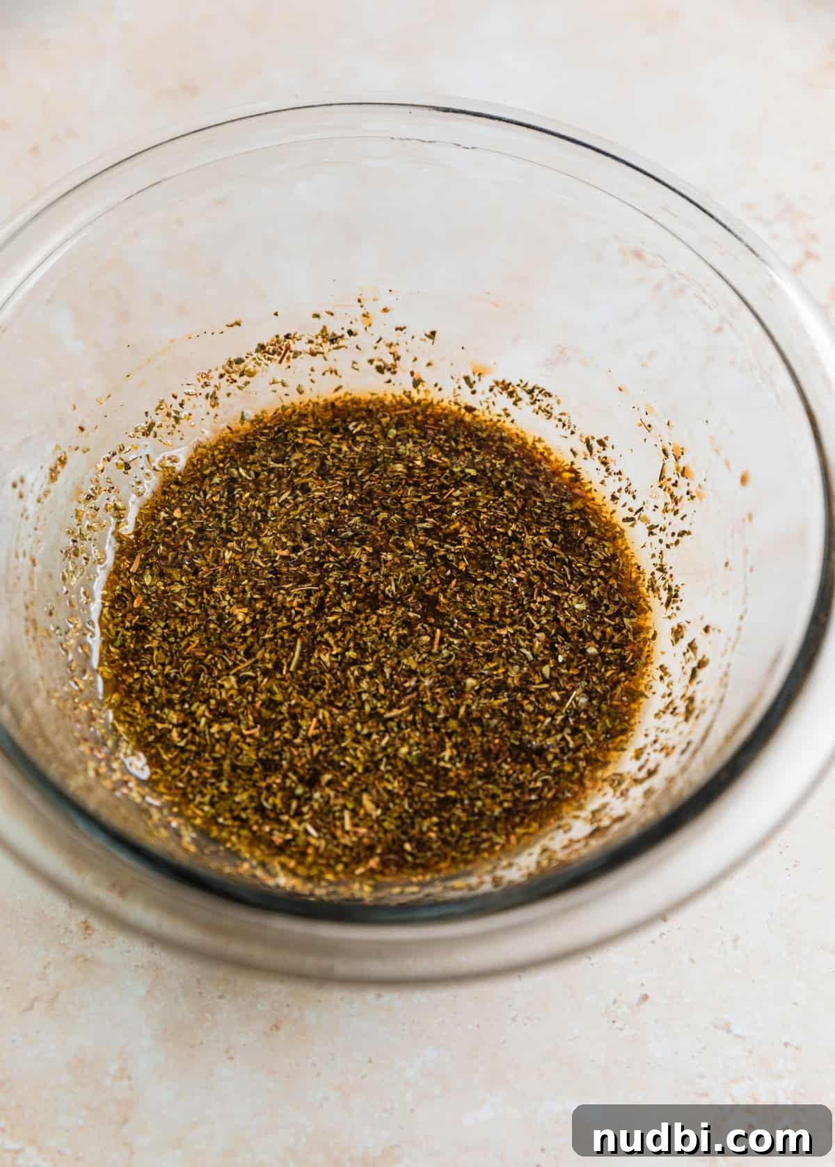 Crispy Air Fryer Steak Bites with Garlic Butter Dip 6 Steak marinade in glass bowl with seasoning.