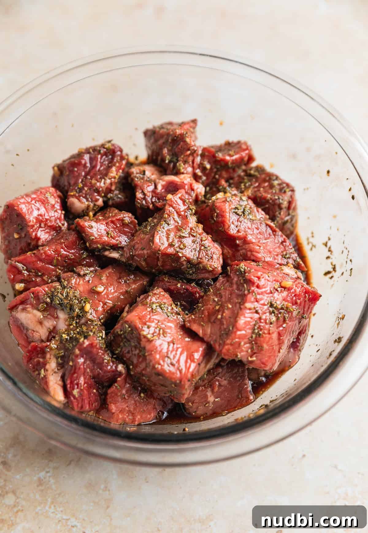 Crispy Air Fryer Steak Bites with Garlic Butter Dip 7 Steak bites in glass mixing bowl tossed with marinade.