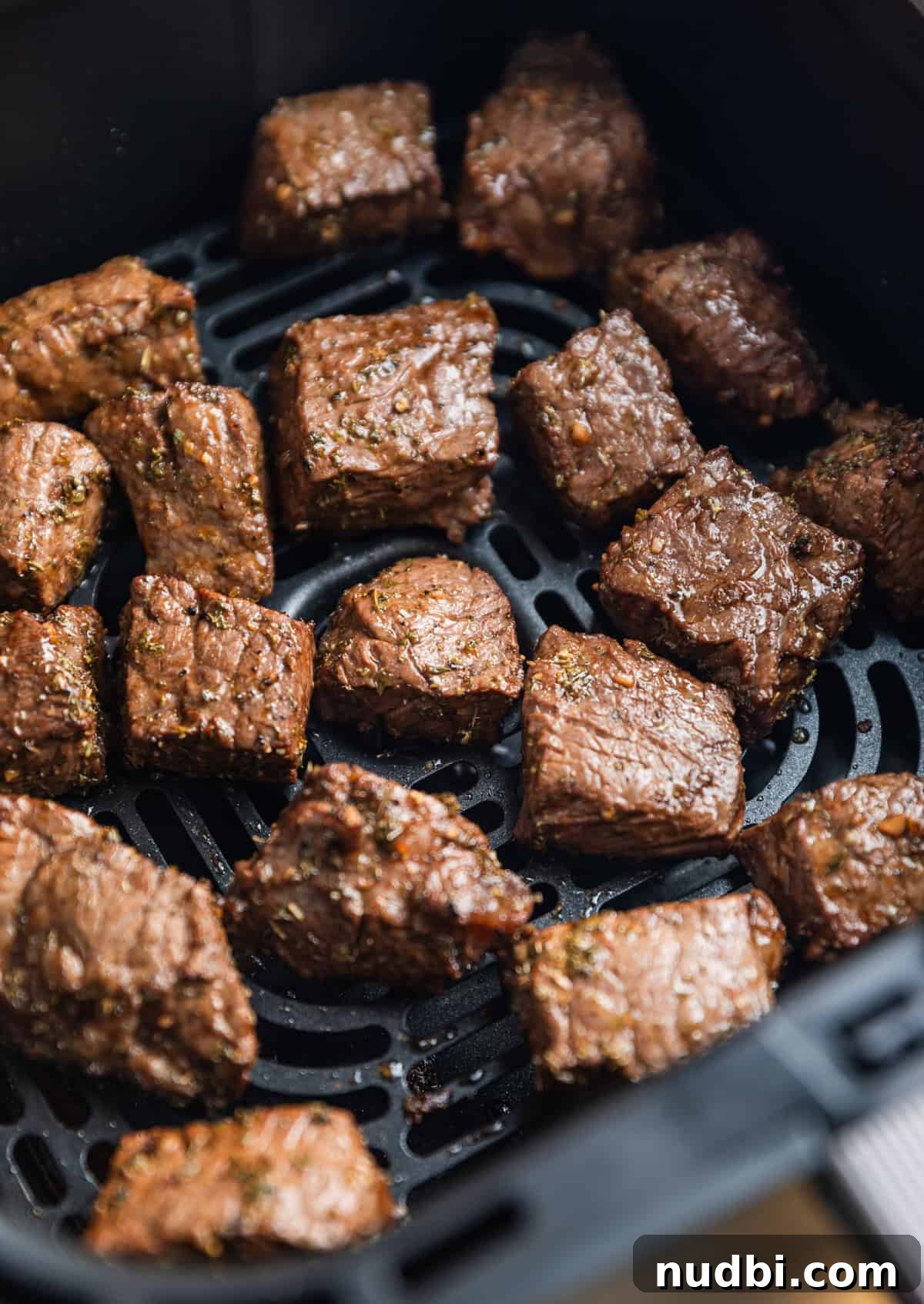 Crispy Air Fryer Steak Bites with Garlic Butter Dip 9 Cooked chunks of sirloin in air fryer basket.