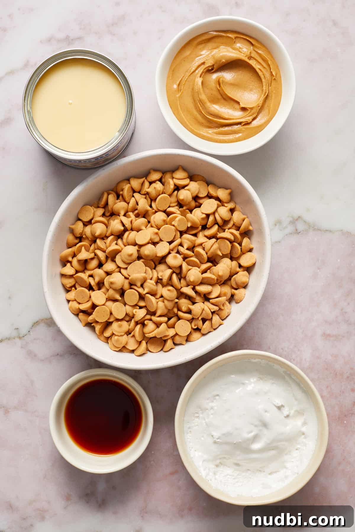 Quick Microwave Peanut Butter Fudge Recipe 3 Peanut butter chips, condensed milk, marshmallow cream and vanilla in bowls on surface.