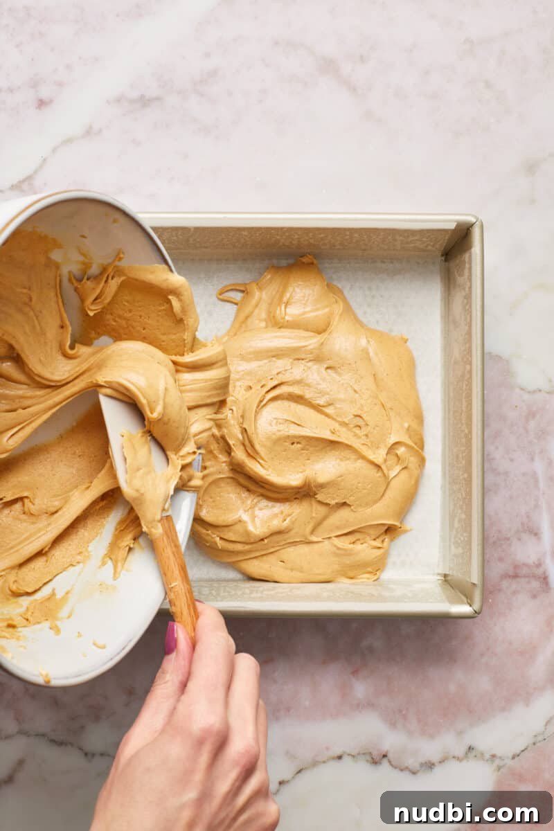 Quick Microwave Peanut Butter Fudge Recipe 7 Peanut butter fudge mixture poured into parchment paper lined baking dish.