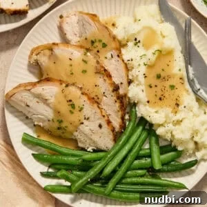Slices of turkey breast on plate with mashed potatoes and green beans.