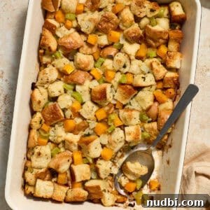 Butternut squash stuffing in pan with serving spoon scooping into the dish.