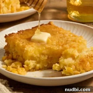 Sweet jiffy cornbread casserole on plate with honey drizzling over top.