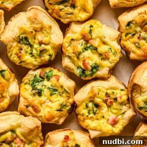 Mini quiches with puff pastry on plate topped with onion and chopped parsley.