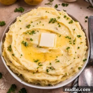 Garlic parmesan mashed potatoes in serving dish with melted butter over top.