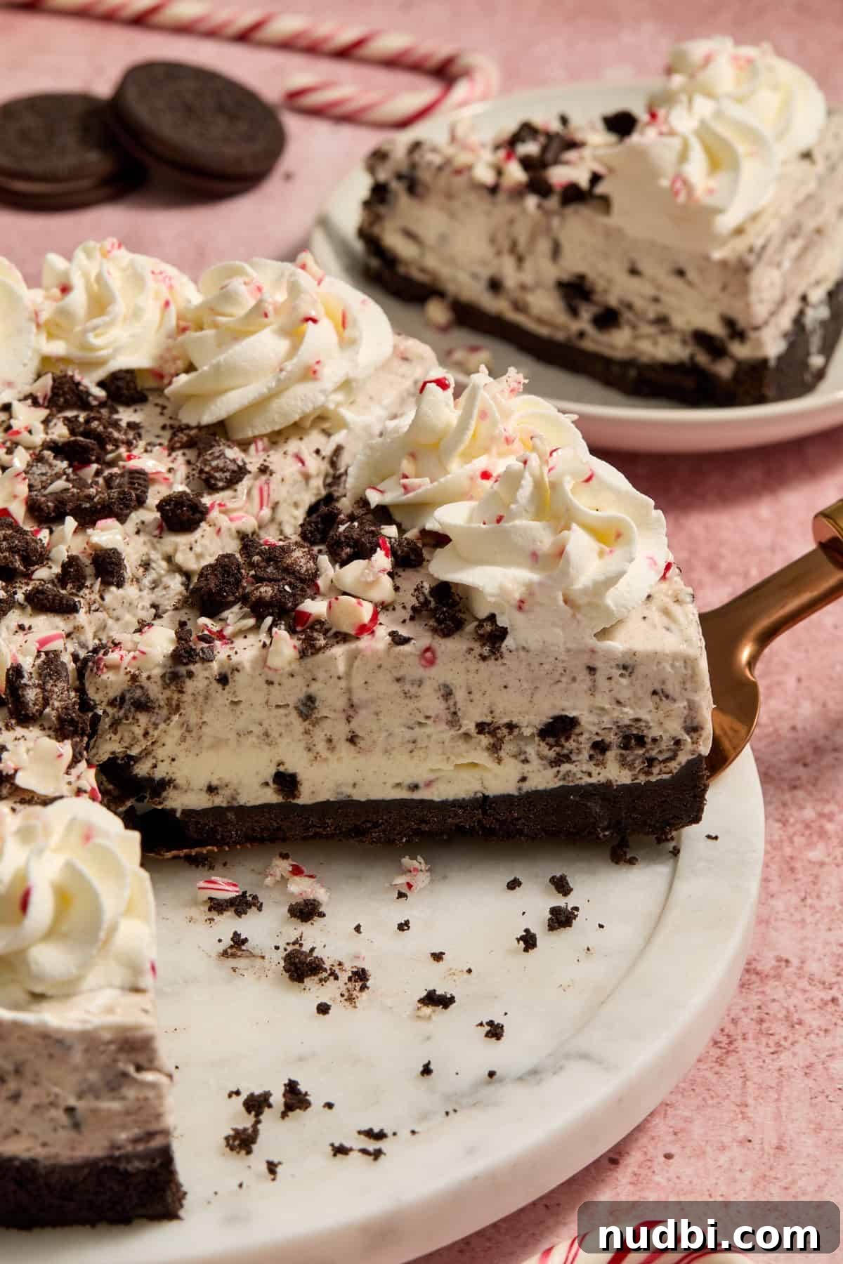 No‑Bake Peppermint Oreo Cheesecake Recipe for the Holidays 2 Slice of no bake peppermint cheesecake with Oreos being picked up by spatula.
