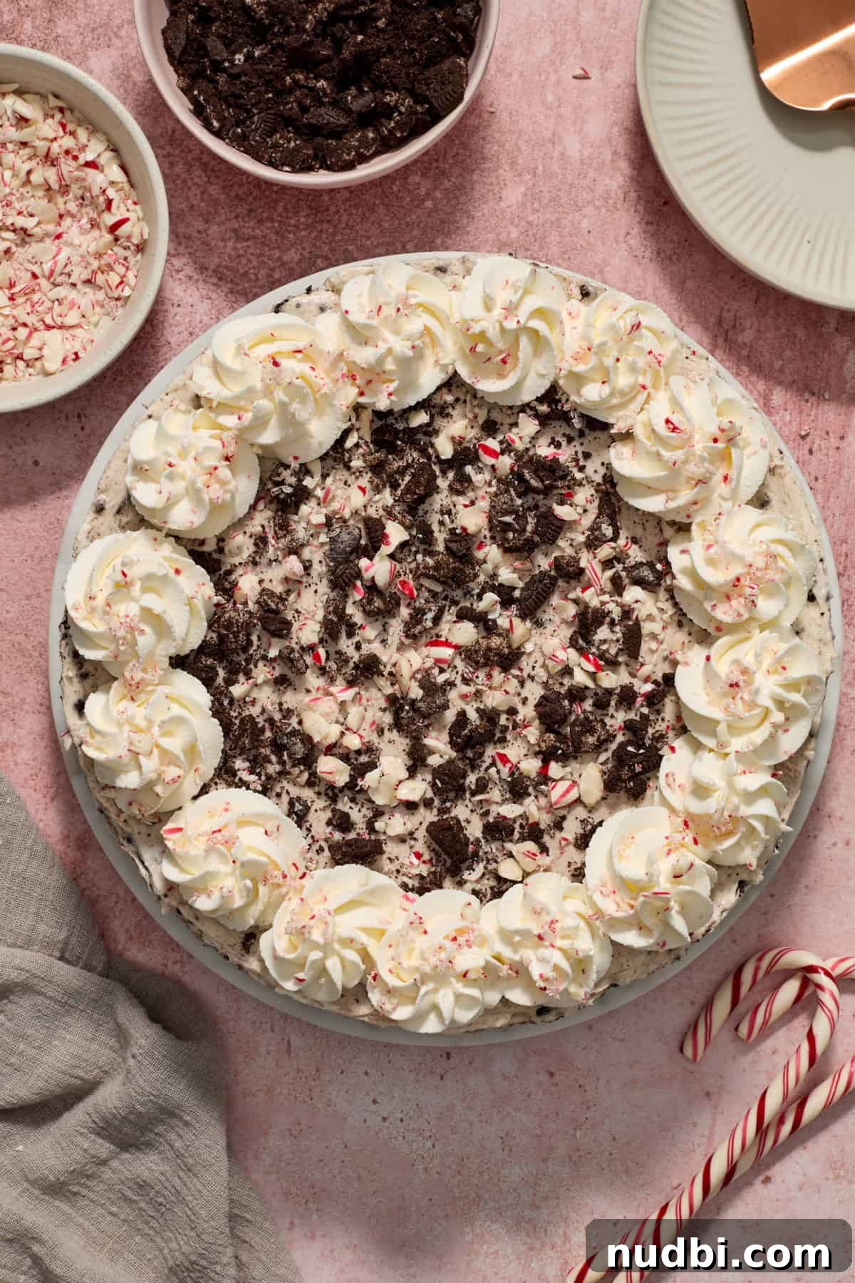 No‑Bake Peppermint Oreo Cheesecake Recipe for the Holidays 18 No bake peppermint Oreo cheesecake with whipped cream around the edges and extra crushed cookies and candy canes on top.