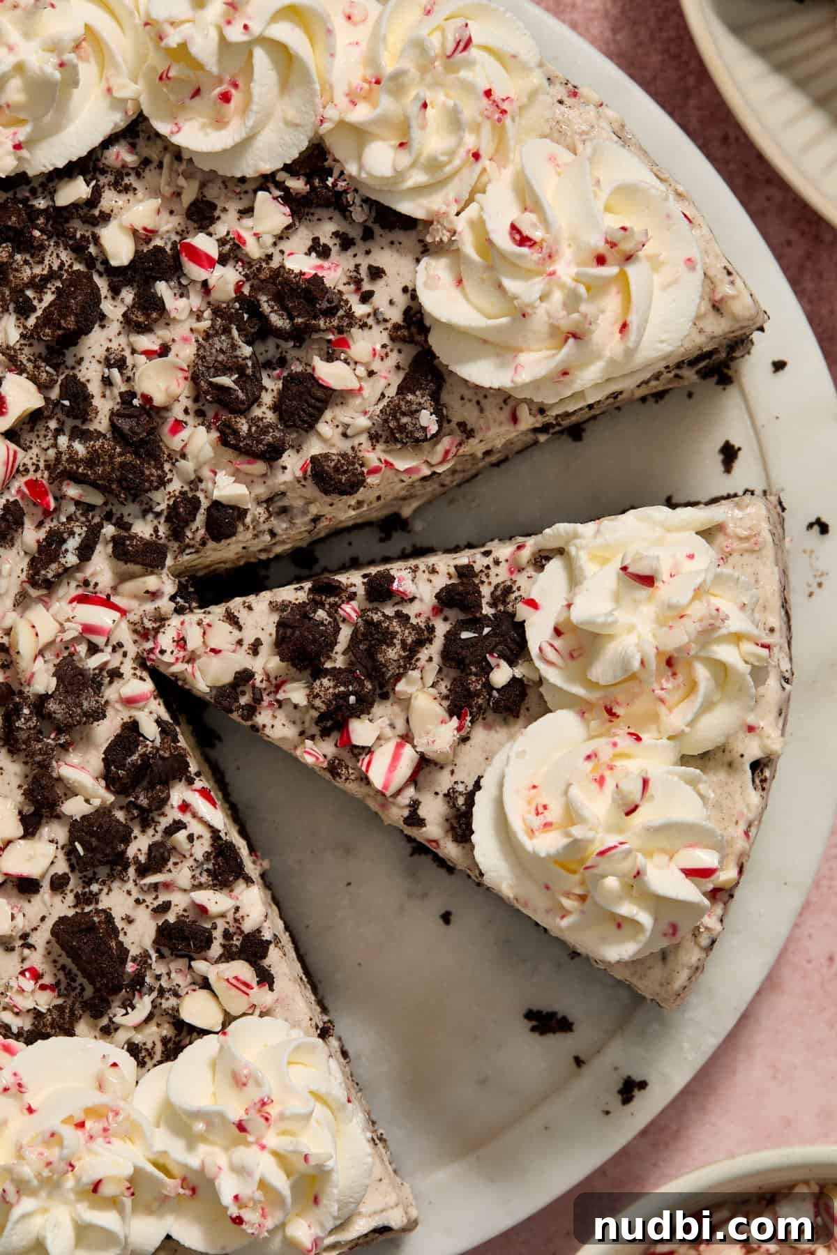 No‑Bake Peppermint Oreo Cheesecake Recipe for the Holidays 3 Slice of cheesecake off set on a pie dish from the rest of the cheesecake.