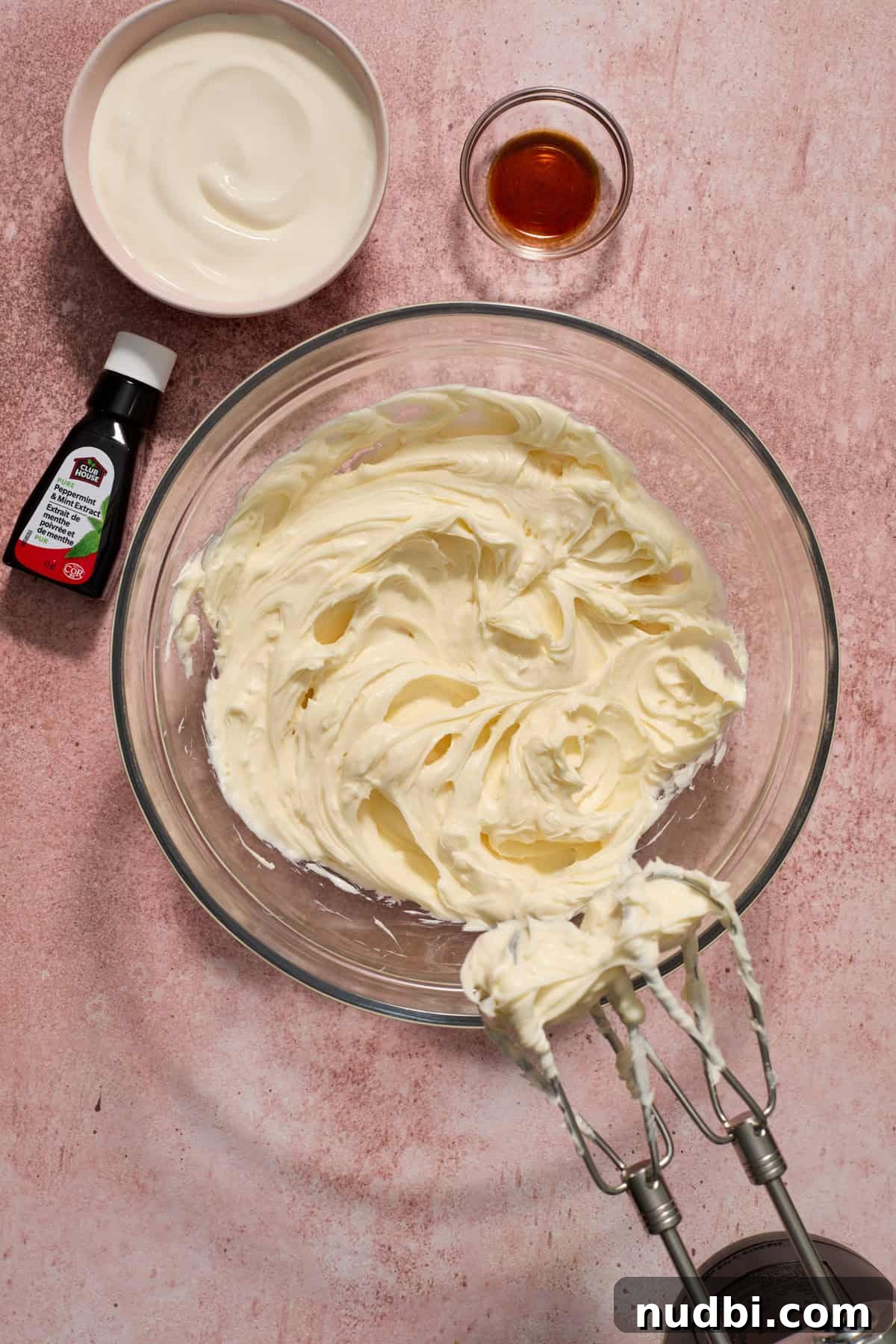 No‑Bake Peppermint Oreo Cheesecake Recipe for the Holidays 9 Whipped cream cheese in mixing bowl with electric hand mixer propped to the side.