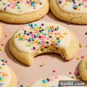 Soft and Chewy Eggless Sugar Cookies Recipe 12 Eggless sugar cookies on surface with bite taken out of cookie.