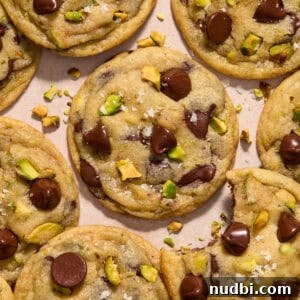 Top Christmas Cookie Recipes to Bake This Holiday Season 15 Pistachio chocolate chip cookies arranged on surface.