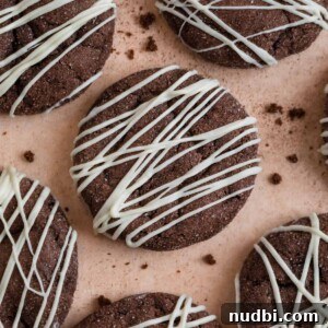Top Christmas Cookie Recipes to Bake This Holiday Season 17 Chocolate cake mix cookies with white chocolate drizzle surrounded by cookie crumbs.