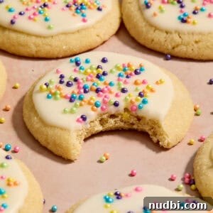 Top Christmas Cookie Recipes to Bake This Holiday Season 19 Eggless sugar cookies on surface with bite taken out of cookie.