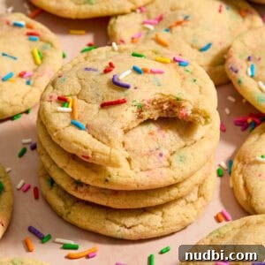 Top Christmas Cookie Recipes to Bake This Holiday Season 26 Stack of funfetti rainbow sprinkle filled cookies with bite taken from the cookie on top of stack.