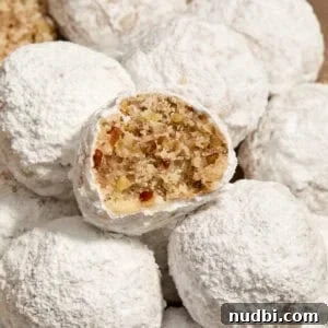 Top Christmas Cookie Recipes to Bake This Holiday Season 8 Pecan snowball cookies with powdered sugar on plate with bite taken out of one cookie.