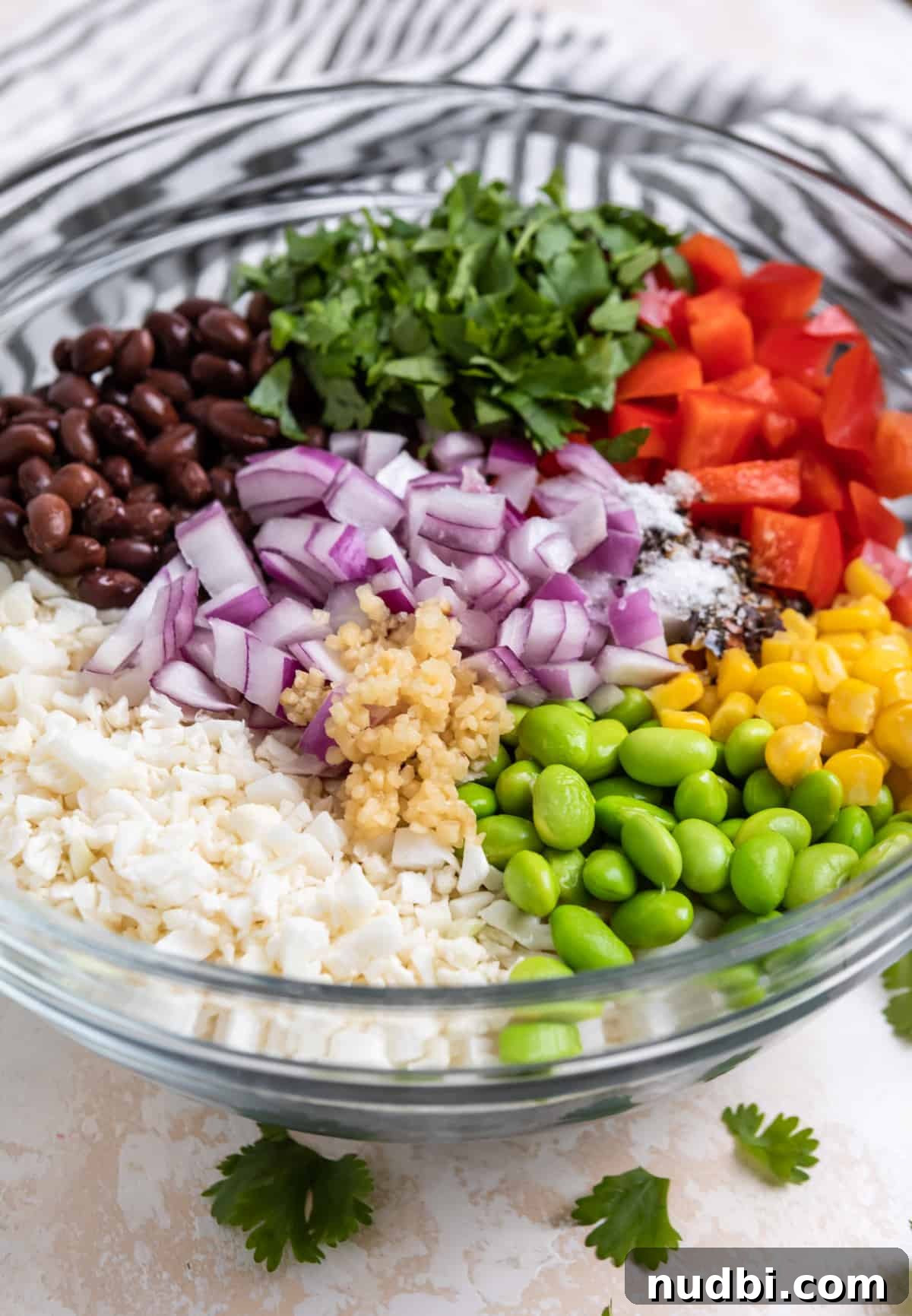 Black Bean & Cauliflower Rice Salad with Zesty Lime Dressing 4 Glass mixing bowl with cauliflower rice, beans, peppers, corn and other salad ingredients.