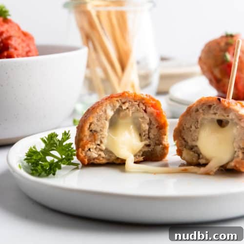 Mozzarella stuffed turkey meatballs on plate with cheese stretching.