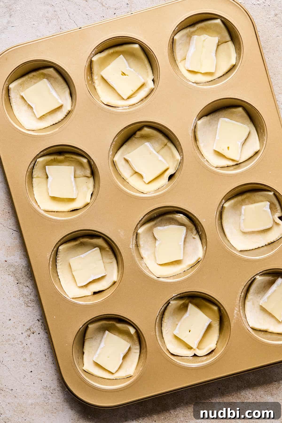 Melted Brie Puff Pastry Bites with Honey & Thyme 5 Muffin tin with puff pastry squares filled with piece of brie cheese.