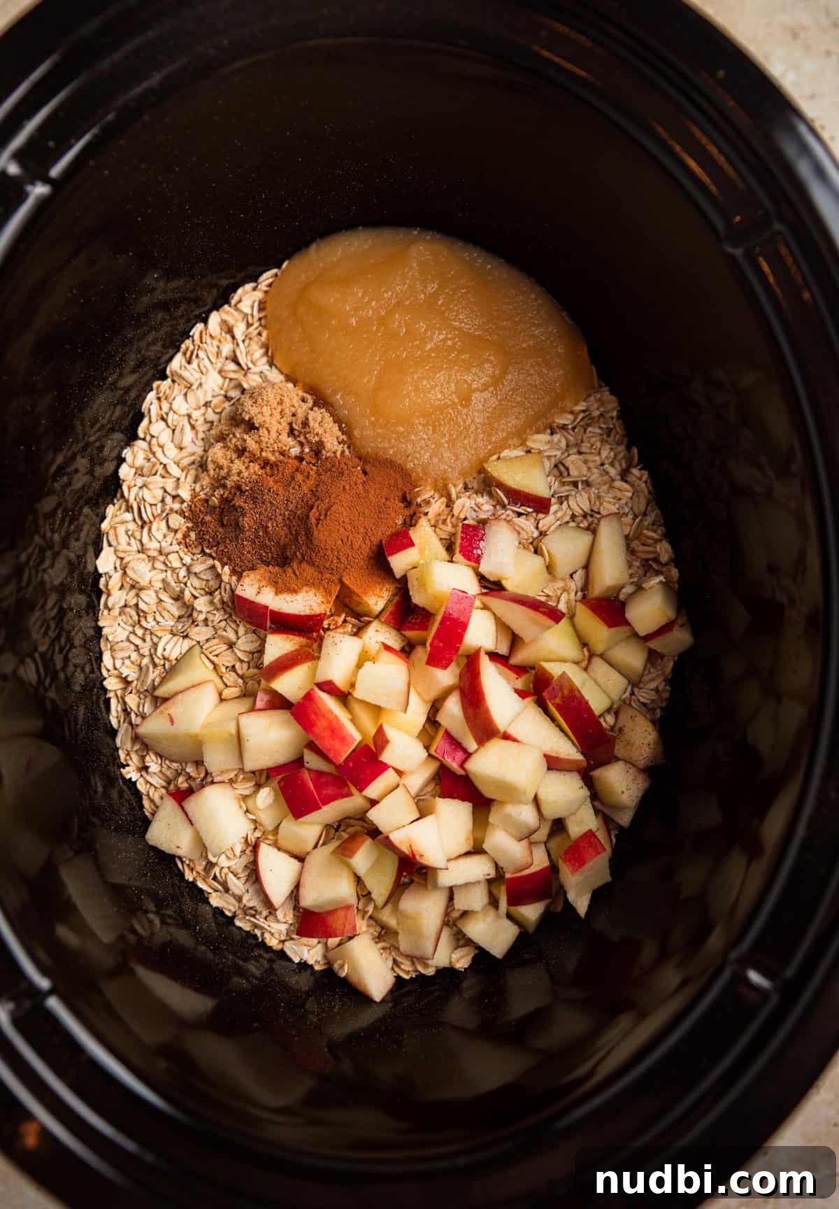 Slow Cooker Apple Cinnamon Oatmeal Recipe for Breakfast 4 Crockpot with rolled oats, diced apples, applesauce, cinnamon and nutmeg.