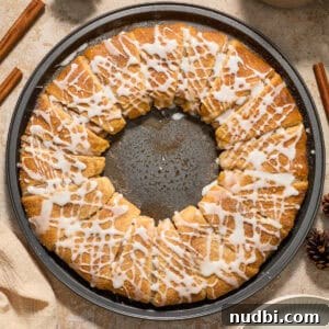Cinnamon crescent wreath on pan with icing drizzle over top.
